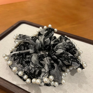 Détail du chouchou gris avec broderie florale noire et décorations en fausses perles