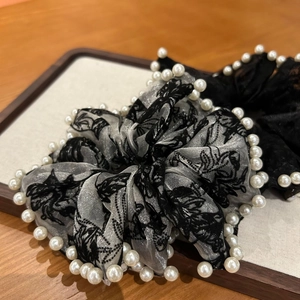 Vue détaillée du chouchou en tulle avec motifs floraux et bordure de perles blanches