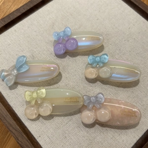 Detail of five colorful acetate cherry and bow hair clips with France Handmade engraving