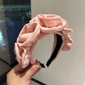 Pink fabric headband with three handmade 3D roses on a comfortable black anti-slip base