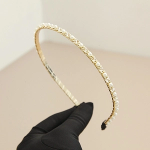 Gros plan du serre-tête doré orné de strass en cristal et de perles blanches fines