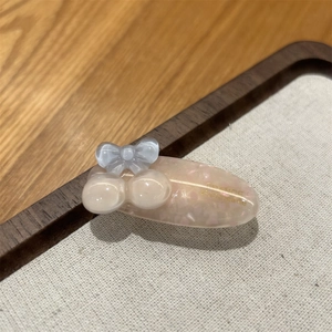 Detailed close-up of pink oval acetate hair clip with glitter and blue bow accent
