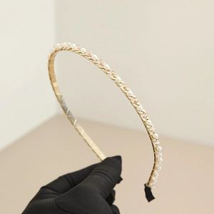 Détail du serre-tête doré avec perles blanches, cristaux roses et embouts noirs antidérapants