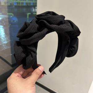 Close-up of the black pleated fabric texture on a wide handmade floral headband