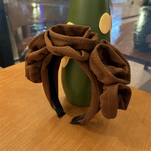 Close-up of brown oversized waffle fabric headband with multiple 3D flower decorations