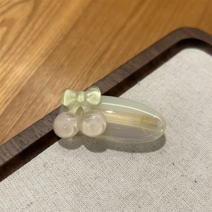Detailed macro of a green acetate hair clip with cherry and bow motif and handmade logo