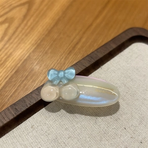 Macro shot of a handmade acetate hair clip featuring a blue bow and pearlescent finish