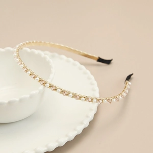 Détail d'un serre-tête doré élégant avec perles blanches et perles de cristal roses