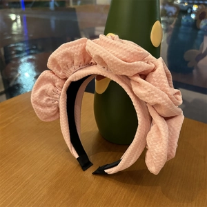 Detail of pink ruffled fabric headband with textured pleated layers on a wooden table
