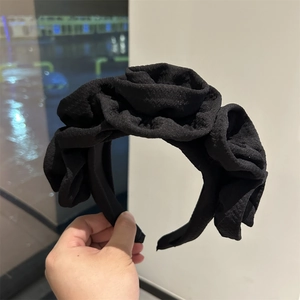 Detail of black fabric headband featuring three large handcrafted fabric rose ornaments