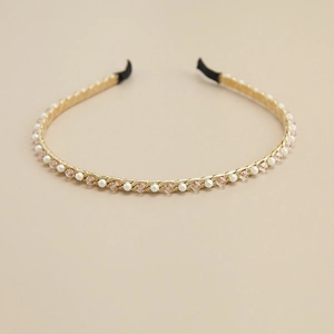 Détail du serre-tête doré avec des perles blanches et des perles de cristal rose