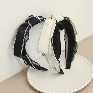 Dettaglio di un cerchietto di lusso con fiocco di strass e bordo in rete nero e bianco crema