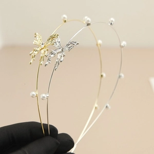 Detail van dubbellaagse metalen haarbanden met goud en zilver vlinderstrikjes en witte parels