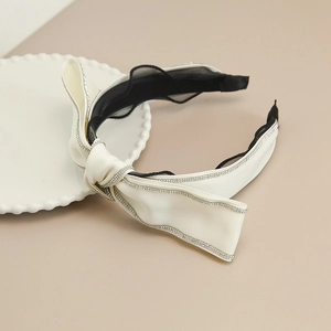 Dettaglio elegante cerchietto a fiocco crema con bordi in strass lucidi