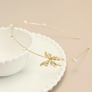 Detail van de gouden metalen haarband met witte parels en holle vlinder versiering