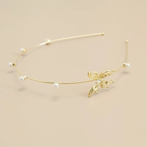 Detail van een dunne gouden metalen haarband met elegante parels en vloeibaar metalen vlinder