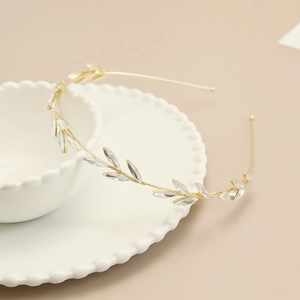Detail of elegant gold leaf headband with clear crystals on a white ceramic bowl