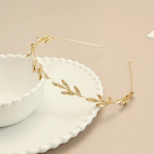 Close-up of golden olive leaf headband with sparkling rhinestones on a white ceramic bowl
