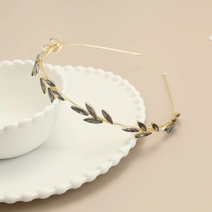 Detail of vintage gold leaf headband with grey rhinestone accents on a ceramic bowl
