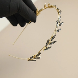 Close-up of golden leaf headband with dark grey rhinestones on a clean background