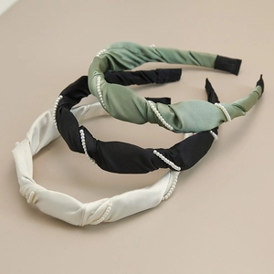 Detailed view of satin twisted headbands with small pearl beads in green, black, and beige