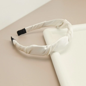 Detailed view of beige satin twisted headband decorated with fine pearls and black anti-slip ends