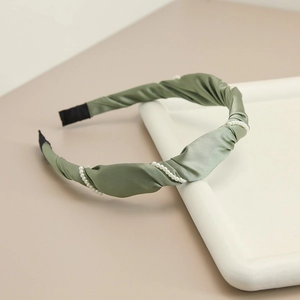 Detail of sage green satin headband with twisted pleats and elegant pearl embellishments
