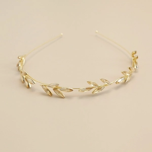 Elegant gold vintage leaf headband featuring champagne rhinestones on a warm beige background