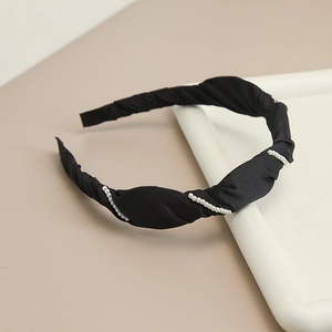 Close-up of black satin pleated headband featuring elegant pearl bead embellishments