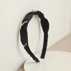 Detail view of retro black satin headband featuring elegant pleated fabric and pearl accents