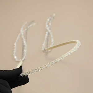 Close-up of handmade beaded headband with sparkling crystals held by gloved hand