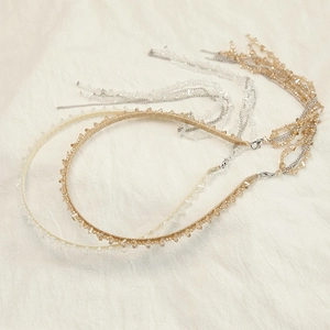 Detail of beaded headbands with crystal tassels and lobster clasps on beige fabric