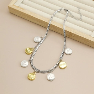 Detail of layered silver chain necklace with pearl beads and engraved gold pendants