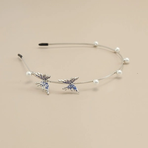 Elegant silver metal butterfly headband with blue accents and pearls on cream background