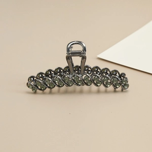 Elegant gunmetal shark hair claw clip with light green rhinestones on beige background