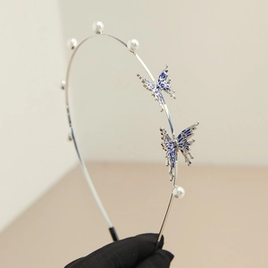Detail of silver butterfly headband with white pearls and blue enamel charms