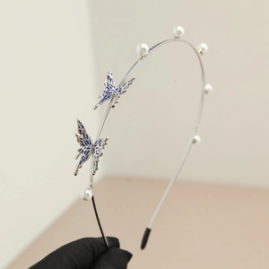 Detail of silver metal headband featuring blue butterflies and white pearls on thin band