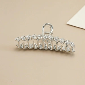 Detail of silver wavy metal hair claw clip with sparkling rhinestones and spring mechanism