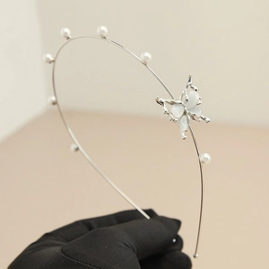 Close-up of elegant silver butterfly headband with white pearls and iridescent wing details