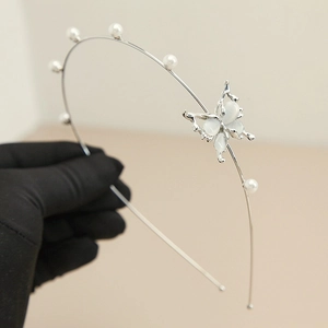 Detail of silver headband featuring blue cat eye stone butterfly and white pearls