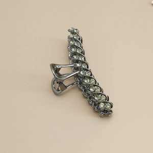 Macro detail of gunmetal alloy hair claw clip with elegant green rhinestones