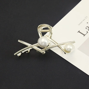 Close-up of minimalist gold metal shark hair claw clip with large white faux pearls