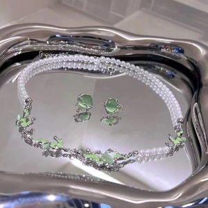 Macro shot of liquid metal necklace set with green cat eye stones on silver tray