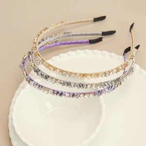 Détail de trois serre-têtes en cristal aux tons champagne, gris et violet élégant