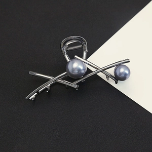 Detail of grey metal claw clip featuring sleek geometric lines and soft grey pearls