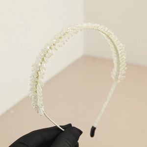 Détail d'un serre-tête de mariée fait main avec perles dégradées et fil doré tressé