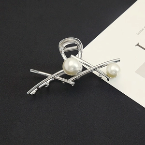 Detail of silver metal geometric hair claw clip featuring large elegant white pearls