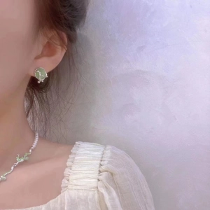 Detail showing elegant cat eye stone necklace with pearl chain worn by a model