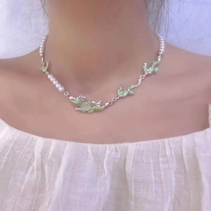 Detail of an irregular green cat's eye stone pendant with pearls on a silver necklace