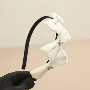 Detailaufnahme von elegantem schwarzem Haarreif mit weißen Satinschleifen und Strass-Schmetterling